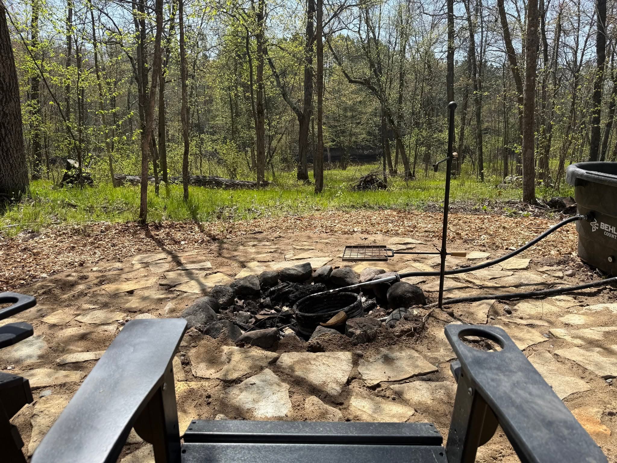 Campfire ring in a sandy clearing surrounded by tall trees