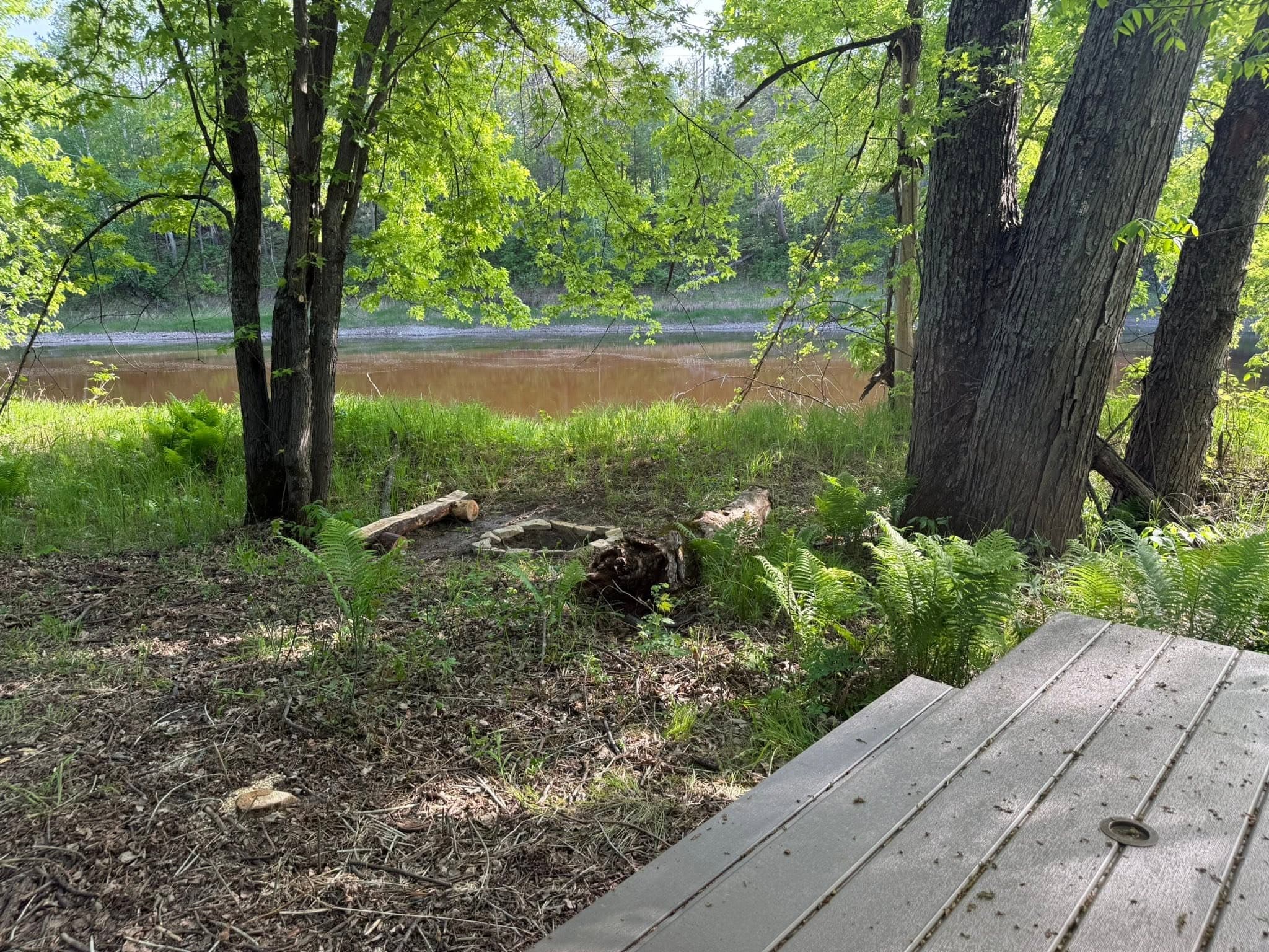 Boardwalk leading to riverside campsite with fire ring