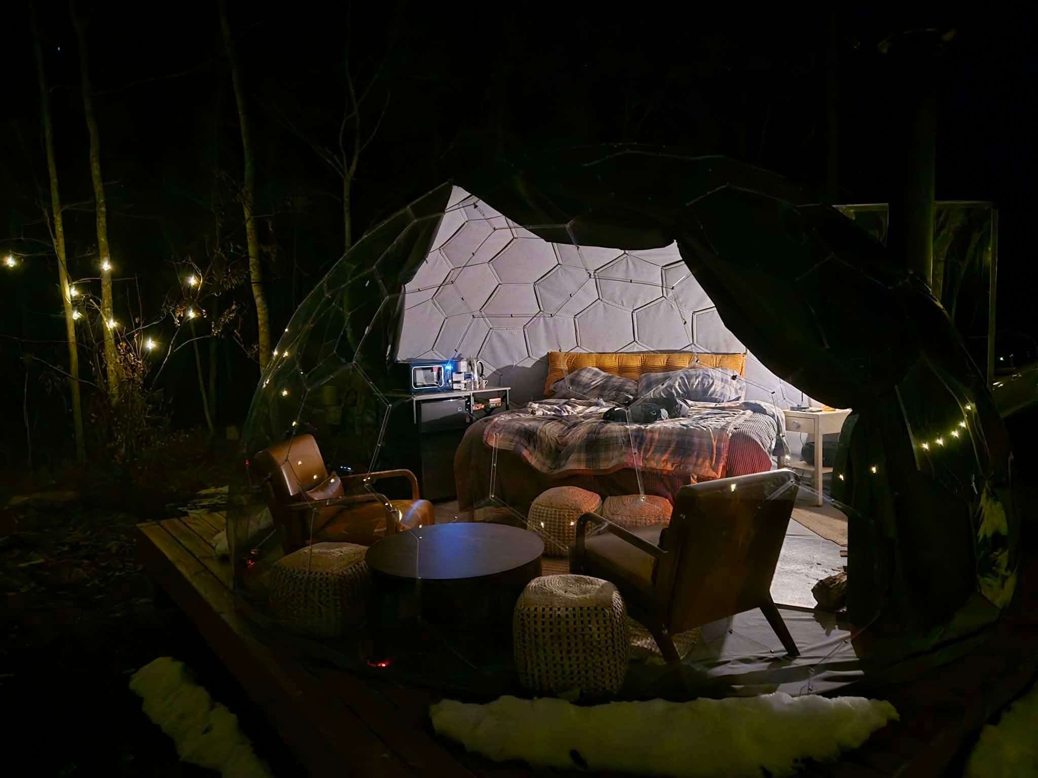 Illuminated glamping dome at night with leather seating and string lights