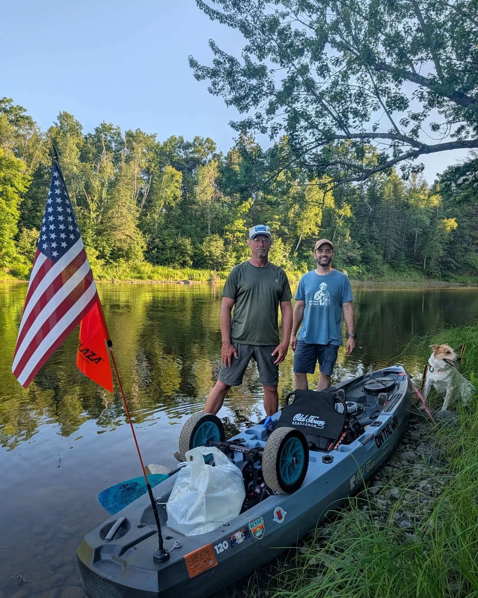 Two people fishing on the river with American flag