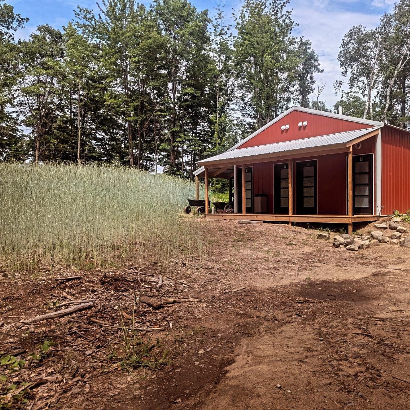 Red-roofed cabin with wooden deck and forest backdrop