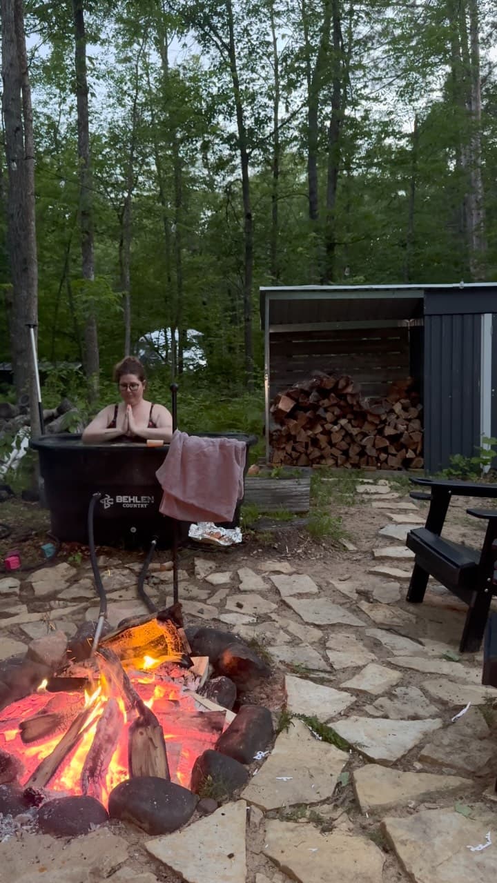 Evening campfire with wood-fired hot tub and firewood storage